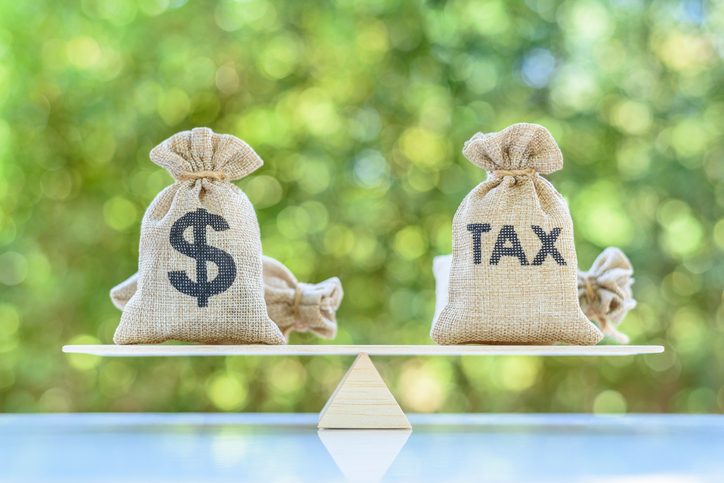 Tax, dollar money bags on a simple balance scale